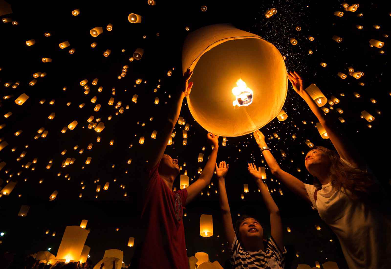 Persone che rilasciano lanterne luminose in un cielo notturno